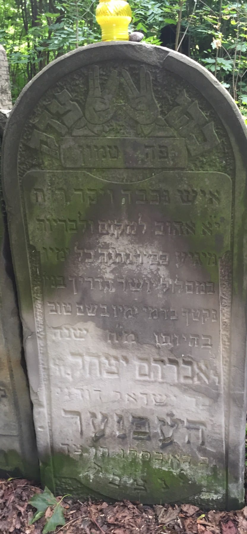 Weathered limestone matzevah with carved priestly hands above a Hebrew inscription, Okopowa Street Jewish Cemetery, Warsaw.